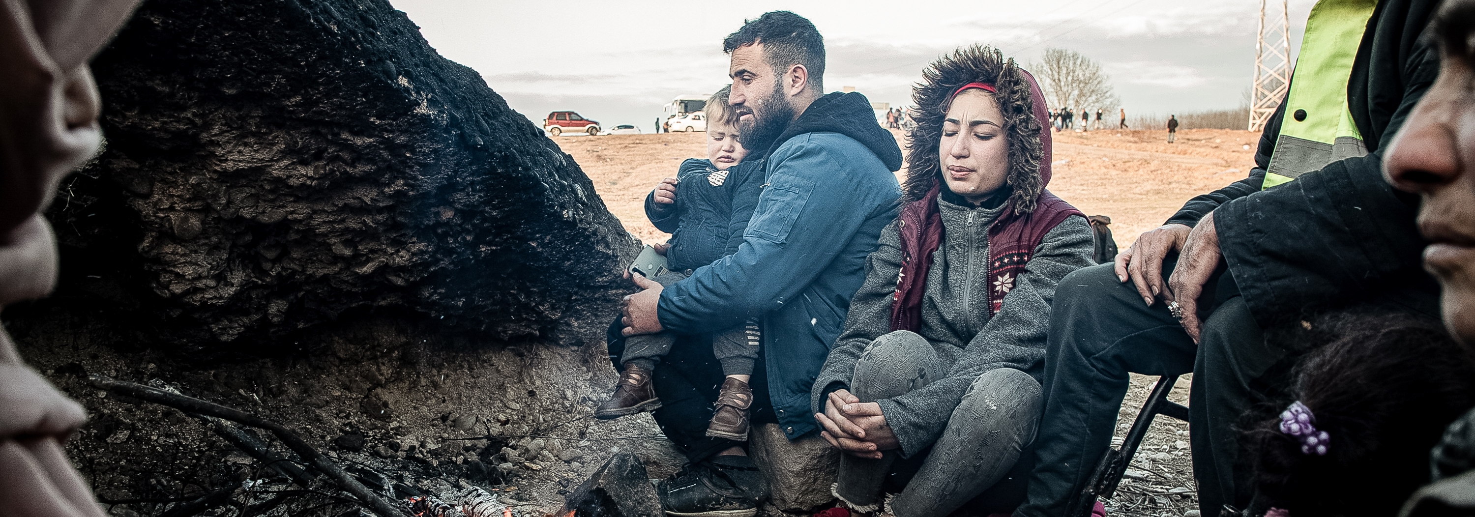 A Syrian family huddles by a fire out of the wind while children gather branches to burn Saturday night as they deliberate how to get home after a failed crossing attempt at the Edirne border with Greece. ©IOM 2020/Emrah Özesen.