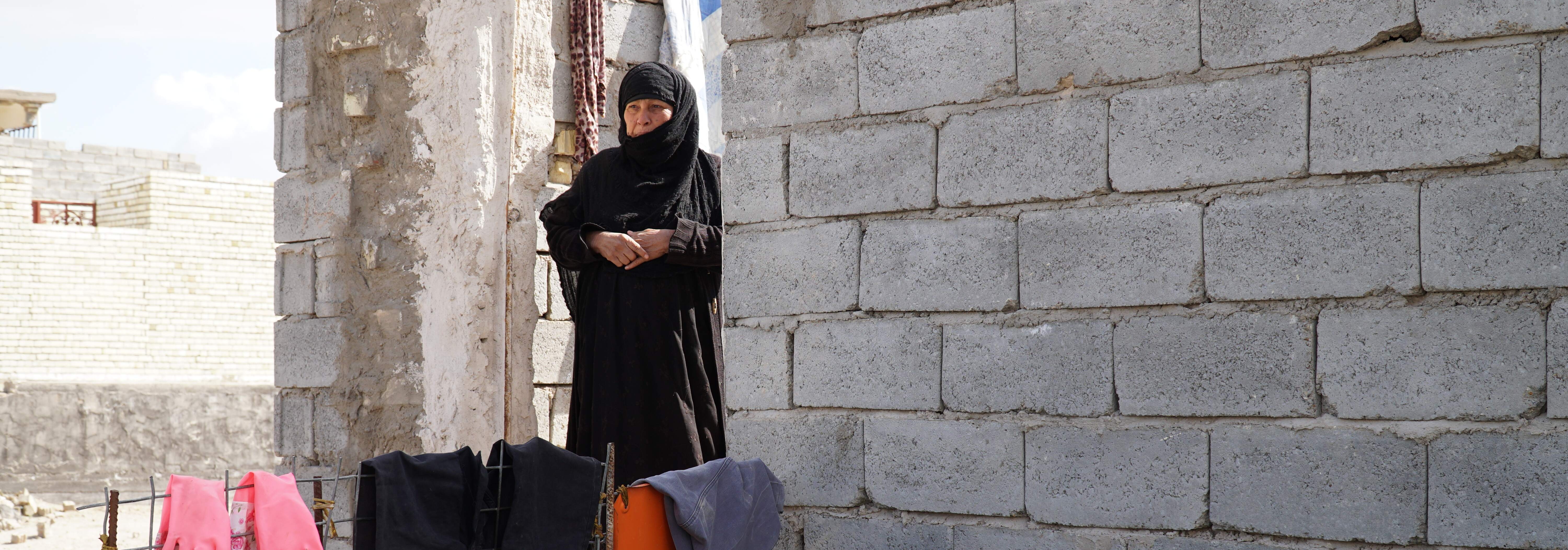 A woman stands near the entrance to her rehabilitated home in Fallujah