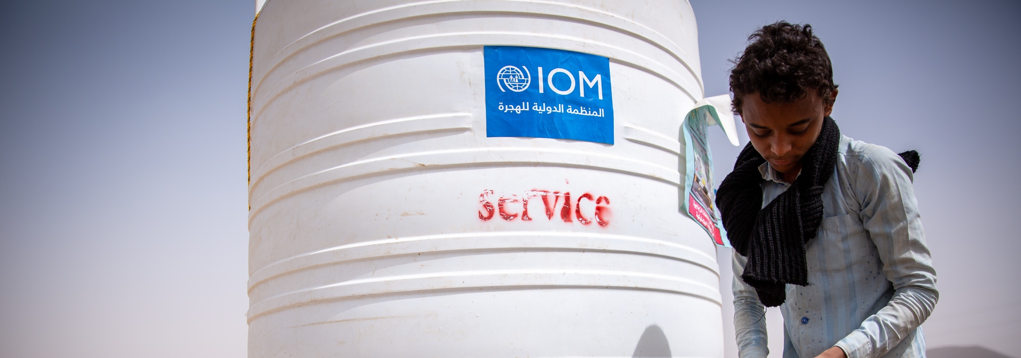 A boy collects water from an IOM tank in a displacement site in Marib governorate where over 100,000 people have been displaced to since the start of the year. Photo: IOM 2020/Olivia Headon